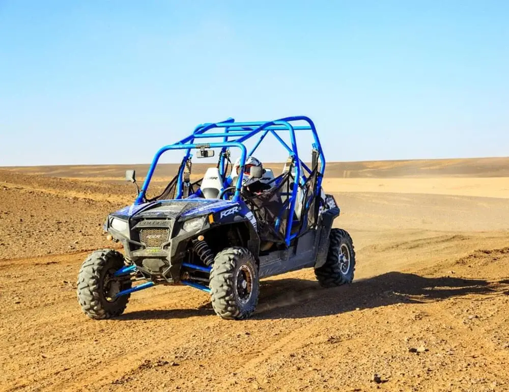 An off-road buggy driving along a dusty track in the Agafay Desert